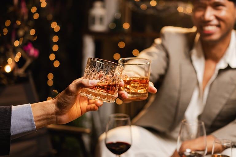 Two men clinking whiskey glasses in celebration