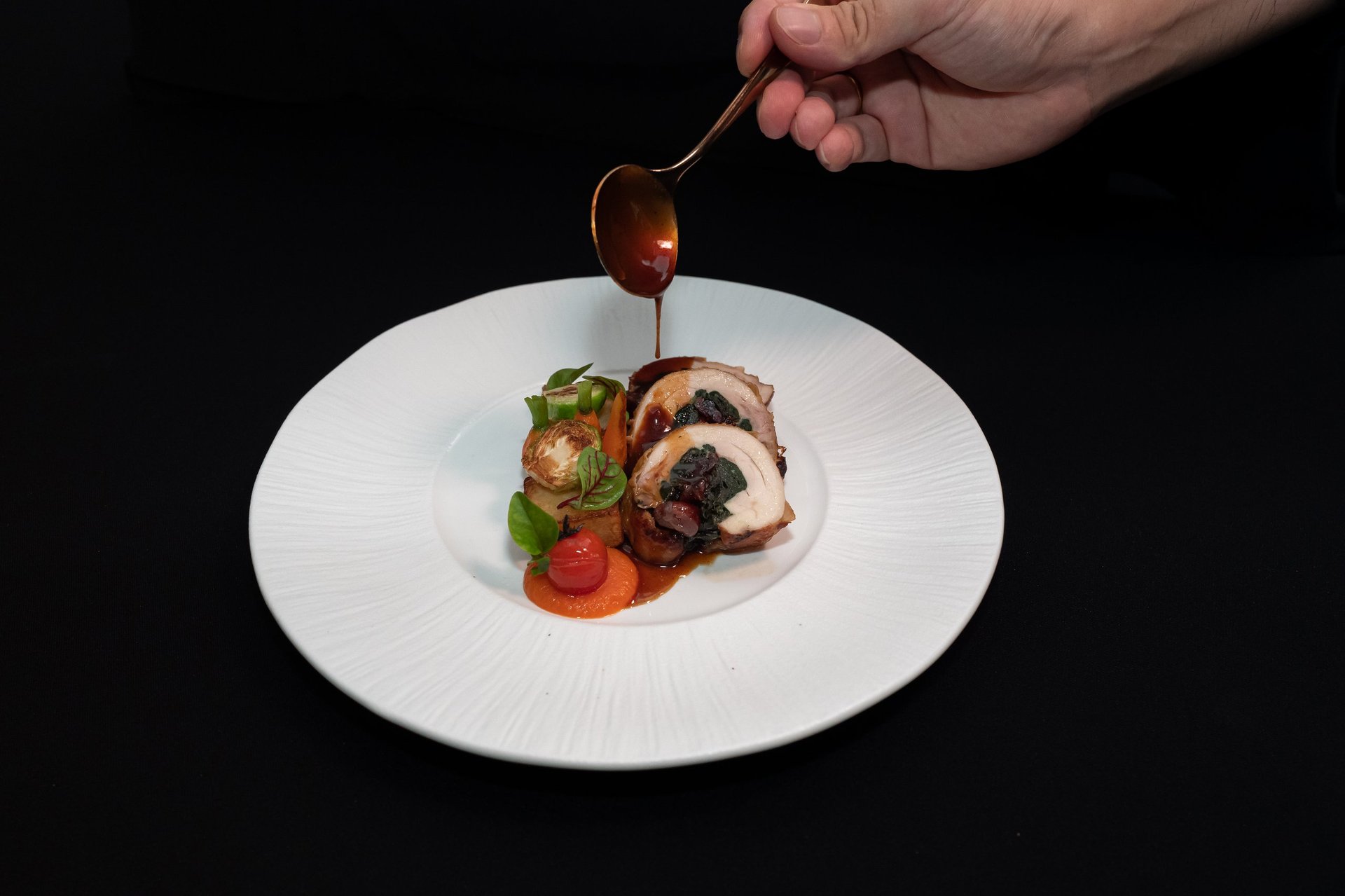 Chef delicately garnishing a beautifully plated gourmet meal