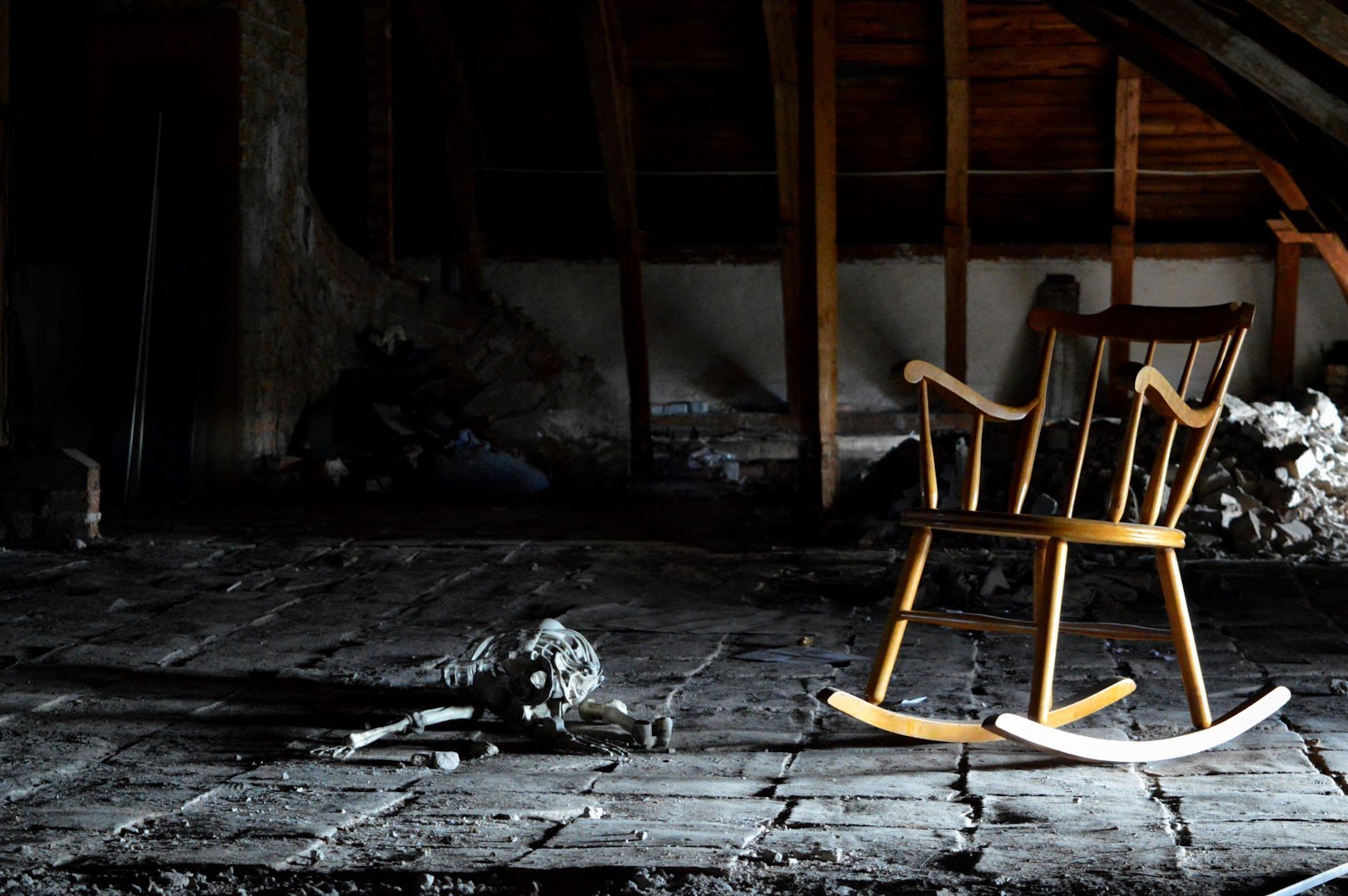 Wooden rocking chair on debris-covered floor in abandoned damaged interior space