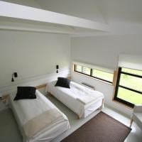 Minimalist bedroom with two twin beds, black pillows, and large windows in a modern space with white walls